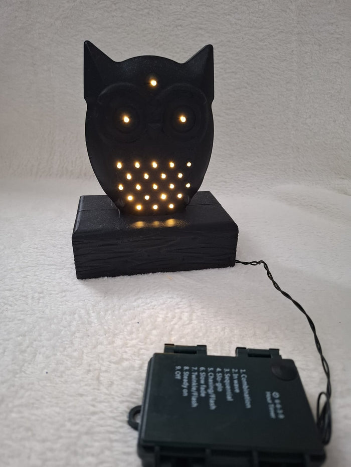 Leucht-Eule mit 24 LEDs – Schwarze Dekofigur auf Holzbalken mit Batteriefach im Sockel