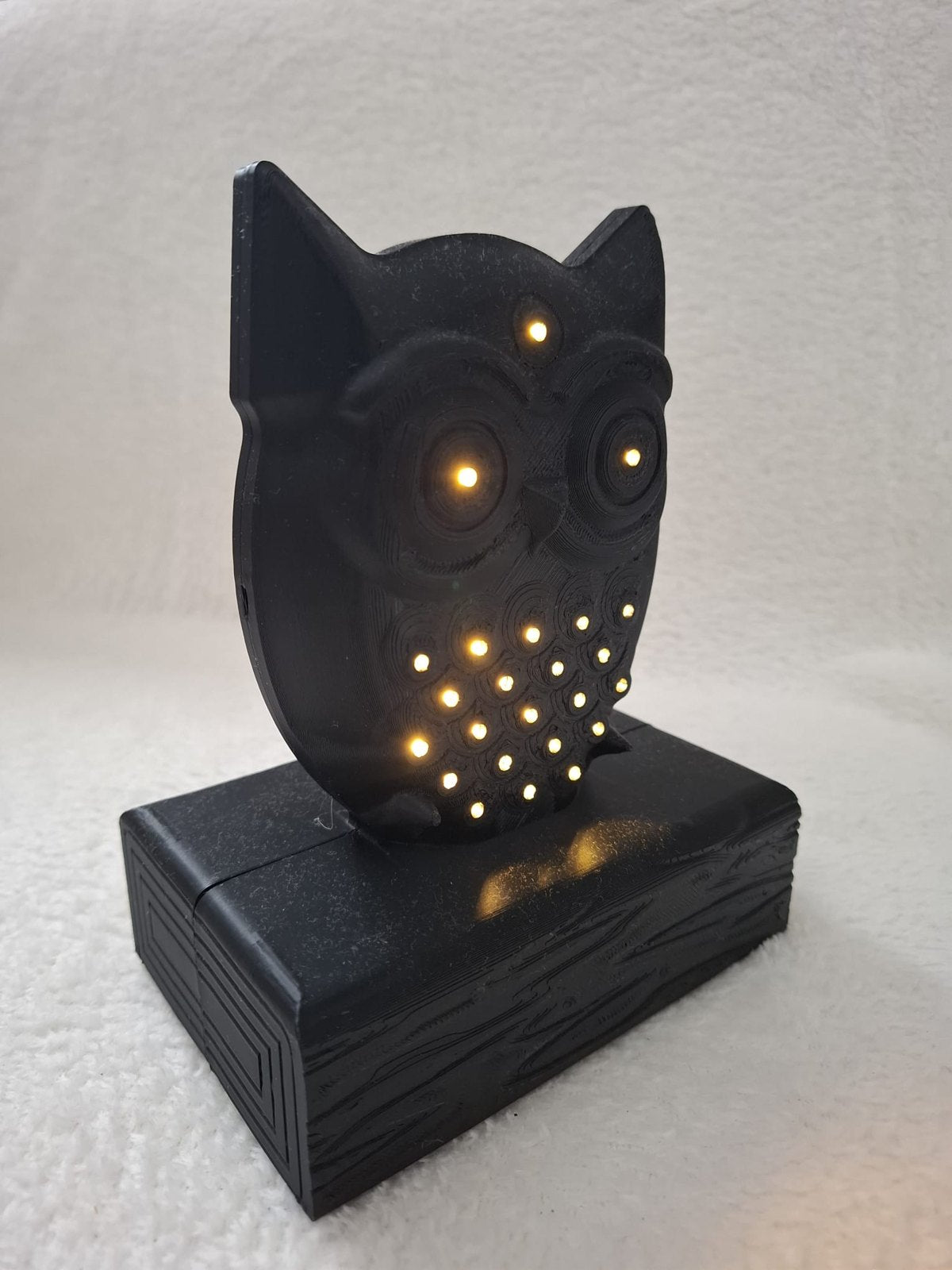 Leucht-Eule mit 24 LEDs – Schwarze Dekofigur auf Holzbalken mit Batteriefach im Sockel