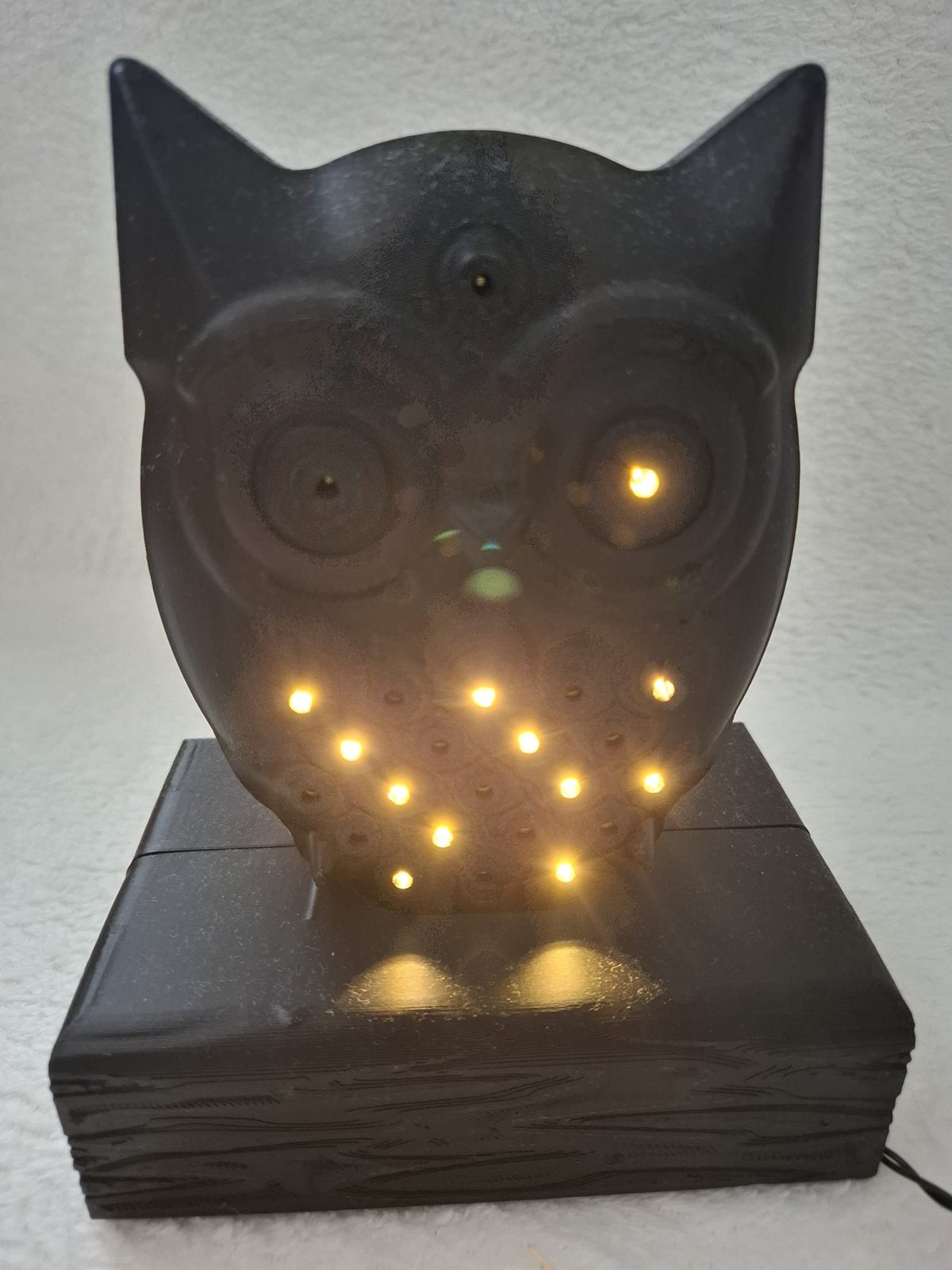 Leucht-Eule mit 24 LEDs – Schwarze Dekofigur auf Holzbalken mit Batteriefach im Sockel